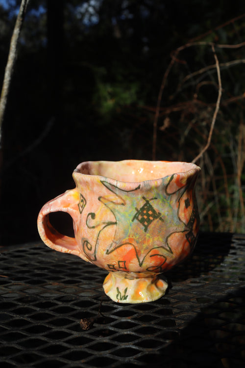 Ceramic mug with abstract designs on a dark surface outdoors