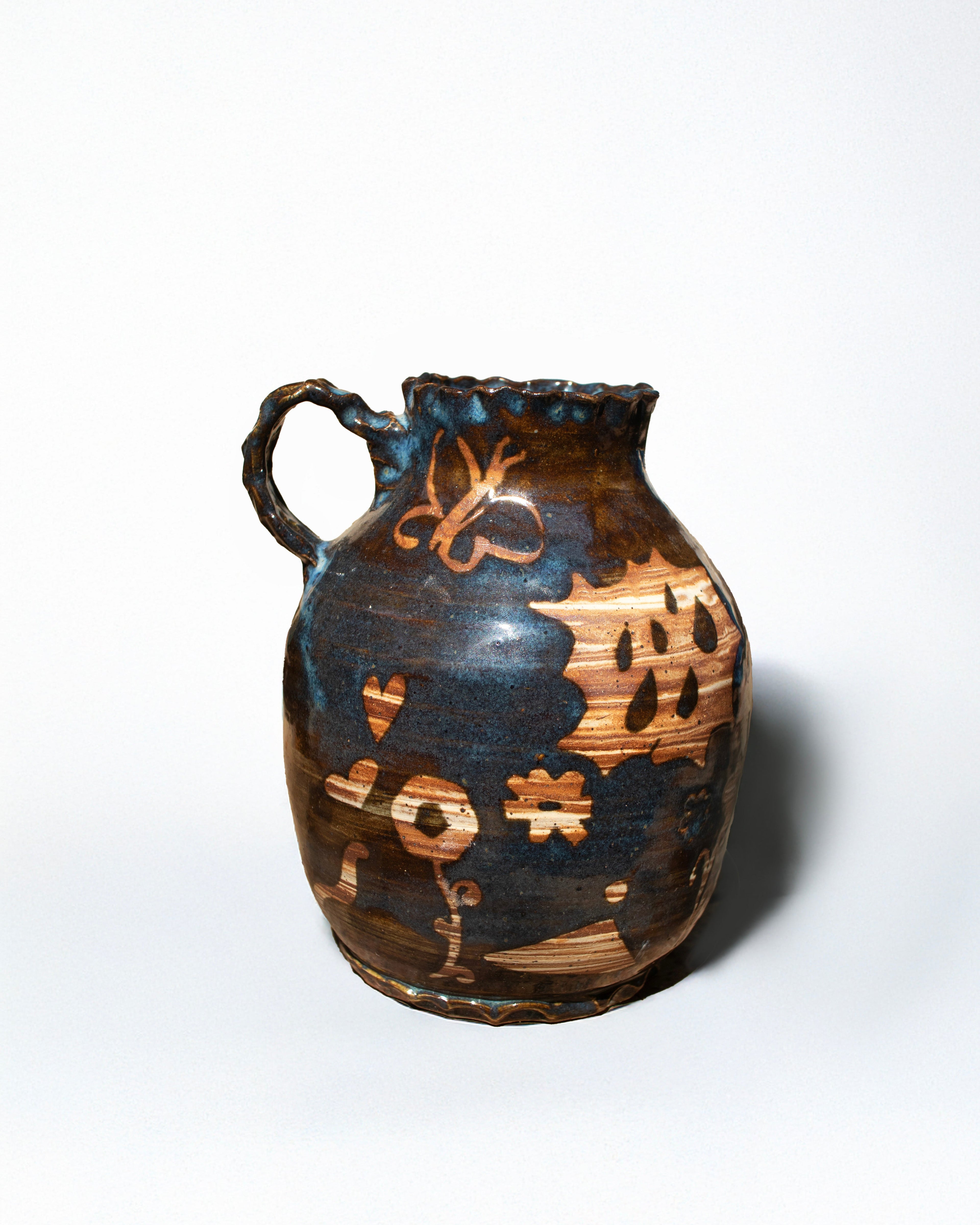 Ceramic pitcher with decorative patterns on a white background